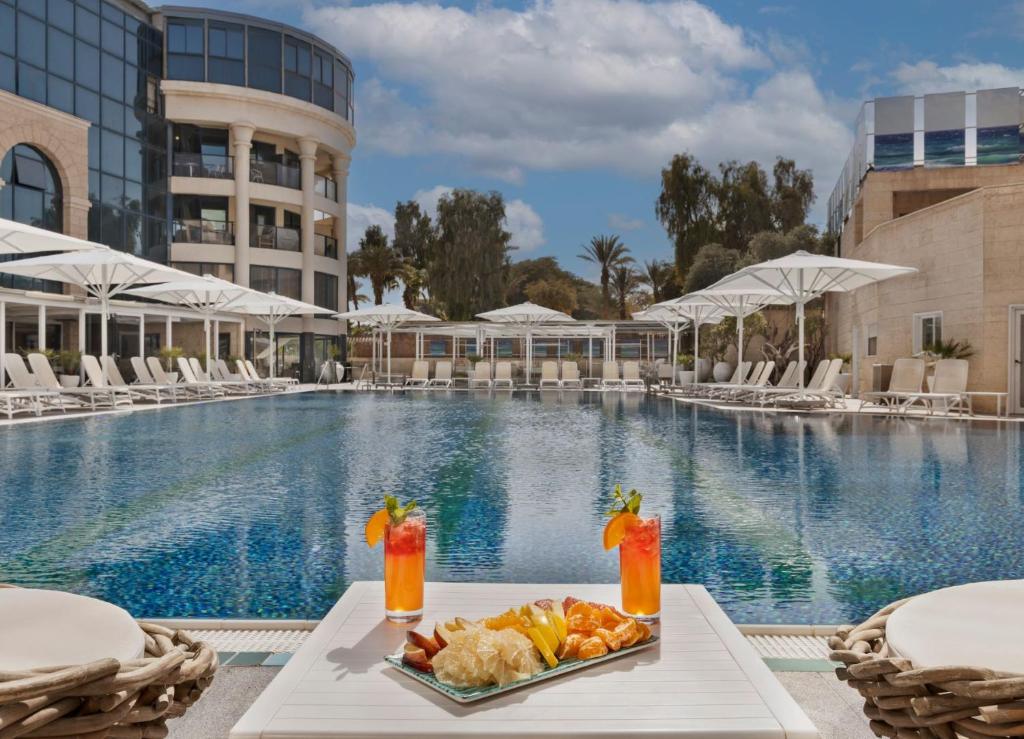 a tray of food on a table next to a swimming pool at The Herbert Eilat - All inclusive Plus in Eilat