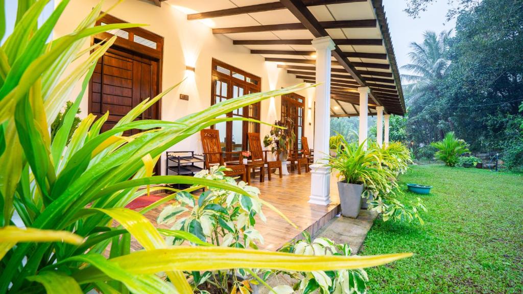 a house with a porch with chairs and plants at Tranquil Guest in Sigiriya