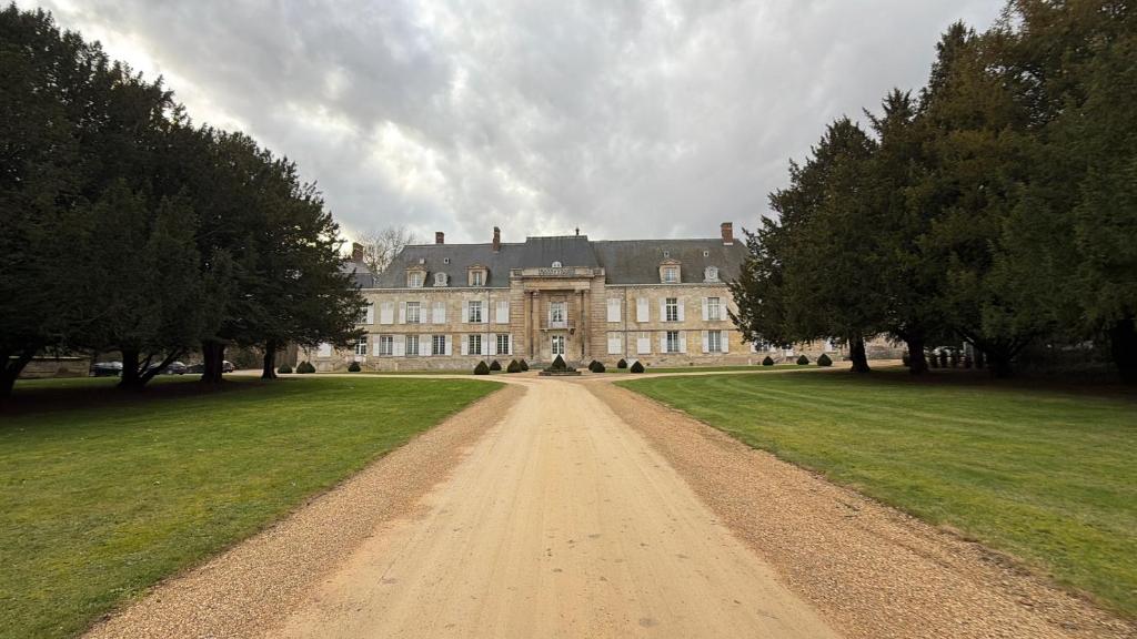 a large house with a dirt road in front of it at Studio au cœur du château in Monchy-Humières