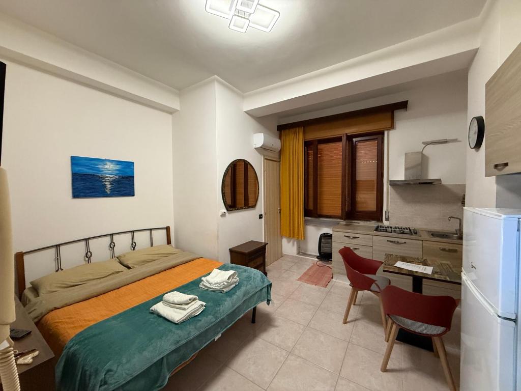 a bedroom with a bed and a table and a kitchen at Monolocale Agesidamo in Locri