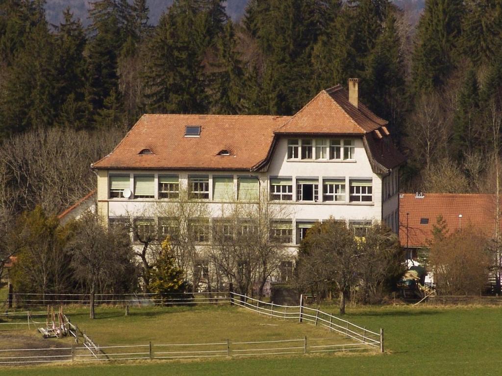 a large white house on top of a field at La Colonie, former watch factory in Les Pommerats