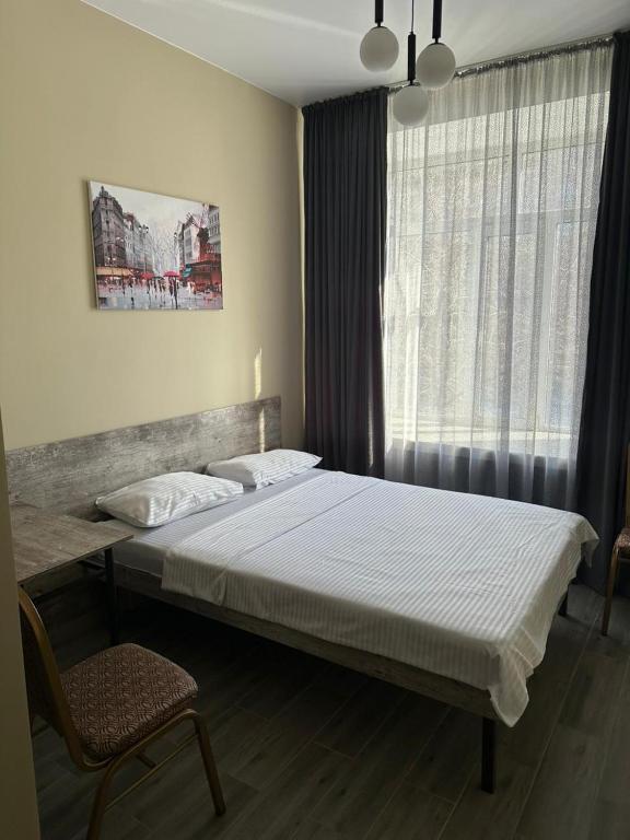 a bedroom with a bed and a chair and a window at Assorti in Semey