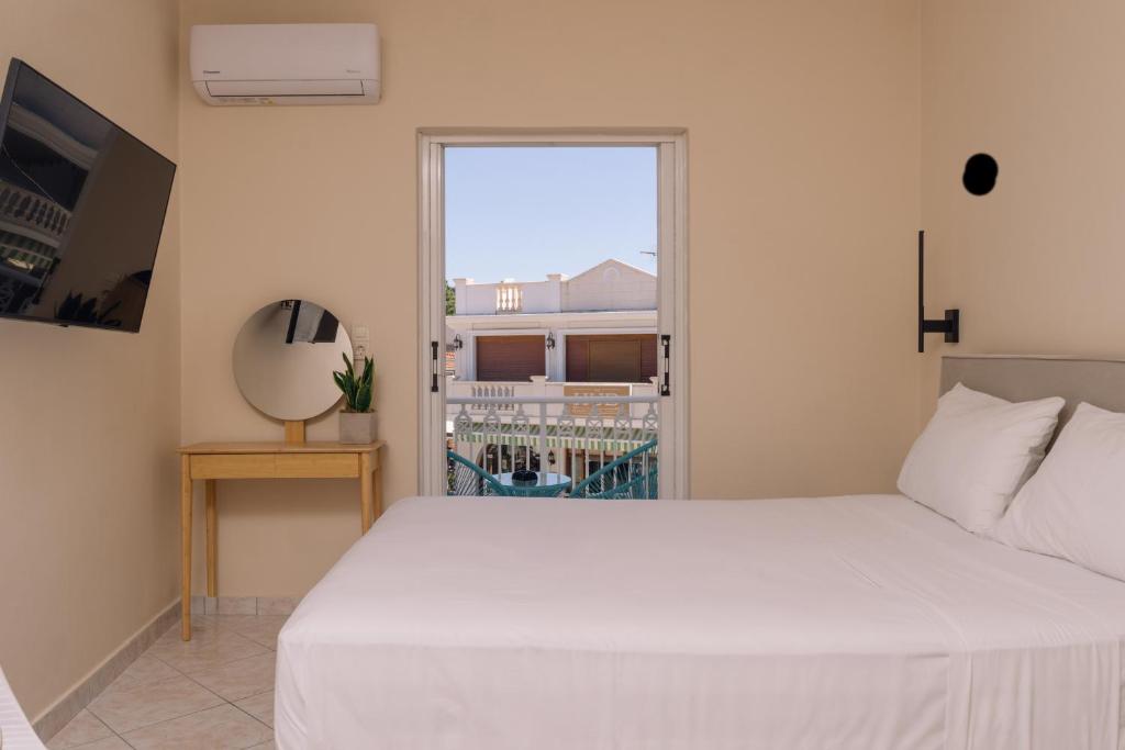 a bedroom with a white bed and a window at Maroudas Apartments in Planos