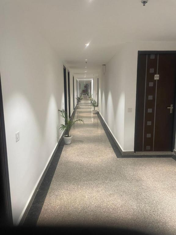 a hallway with white walls and a stairway with a plant at Cozy Inn Hotel in Noida