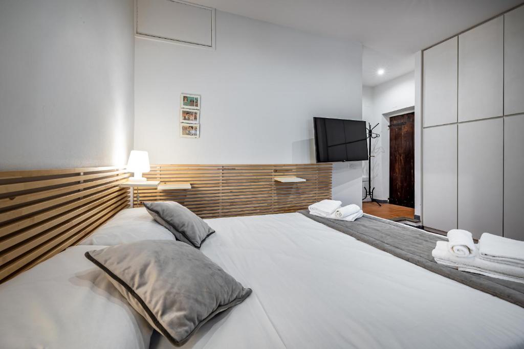 a large white bed in a room with a television at Roommo Via dei Pilastri giada in Florence