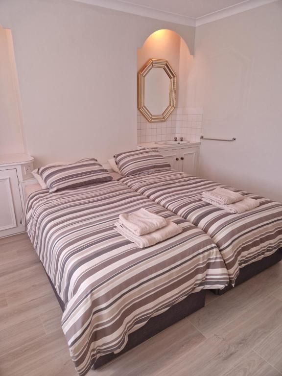 two beds in a bedroom with a mirror on the wall at Osterley Room in Isleworth