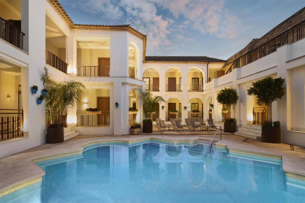 a swimming pool in front of a building with a mansion at NH Collection Palacio de Córdoba in Córdoba