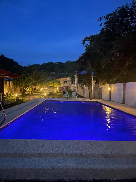 a large blue swimming pool at night at KJT Travellers Inn in Guindulman