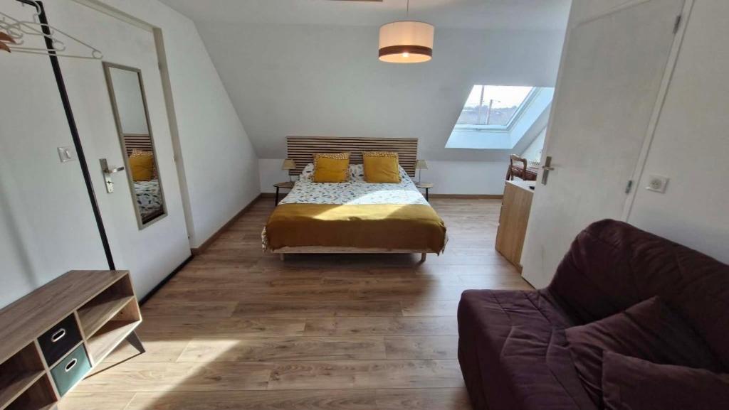 a bedroom with a bed with yellow pillows and a couch at Chambre confortable chez Isabelle in Cléden-Cap-Sizun