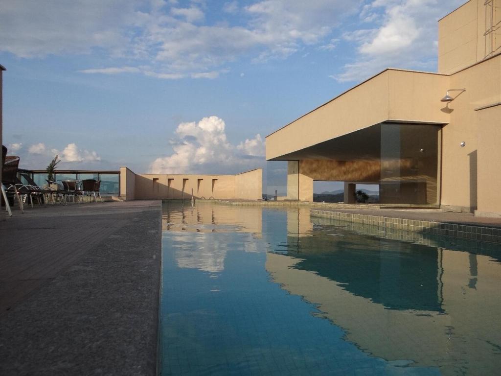 a building with a swimming pool in front of it at Residence Flat Prime Itaboraí in Itaboraí