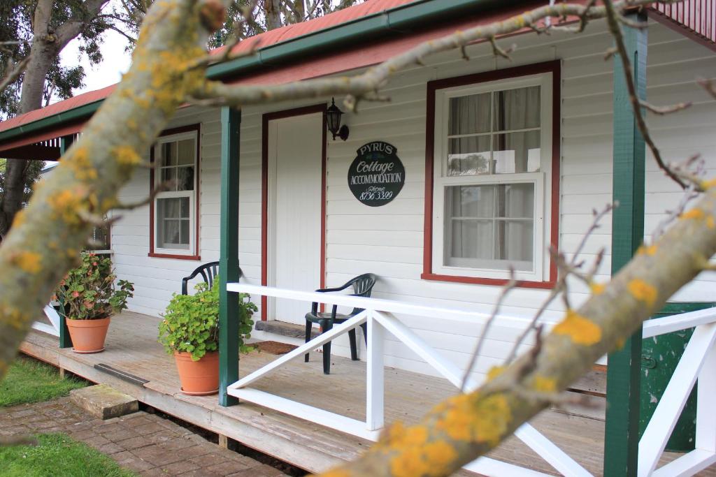 a white house with a porch and a door at Coonawarra's Pyrus Cottage in Coonawarra