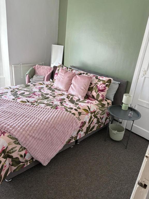 a bedroom with a bed with pink pillows and a table at stylish new house sleeps 5 max in Swansea