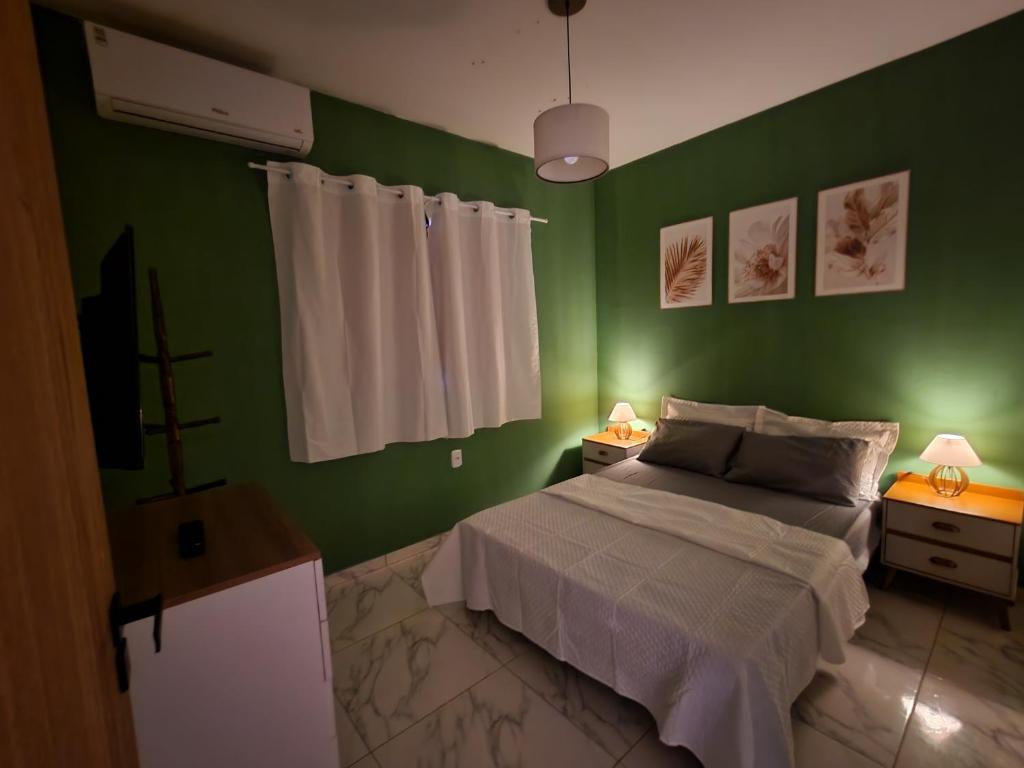 a bedroom with green walls and a bed and two lamps at Lar de verão casa 01 in Barra de São Miguel