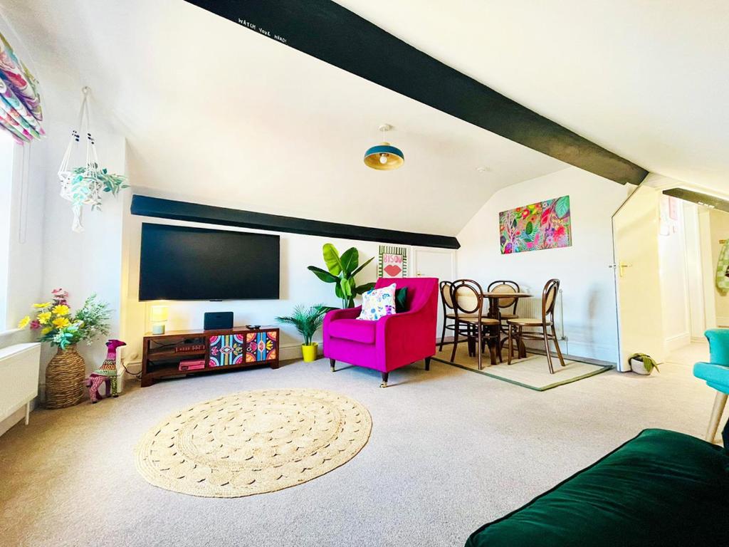 a living room with a pink couch and a flat screen tv at Langdale Loft - Whitby in Whitby
