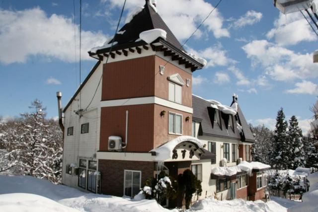 a large building with a snow covered roof at Asuka Lodge in Hakuba