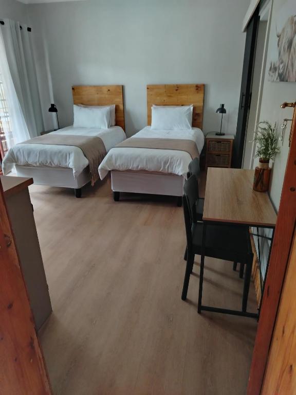 two beds in a room with a table and a desk at KarooRus in Burgersdorp