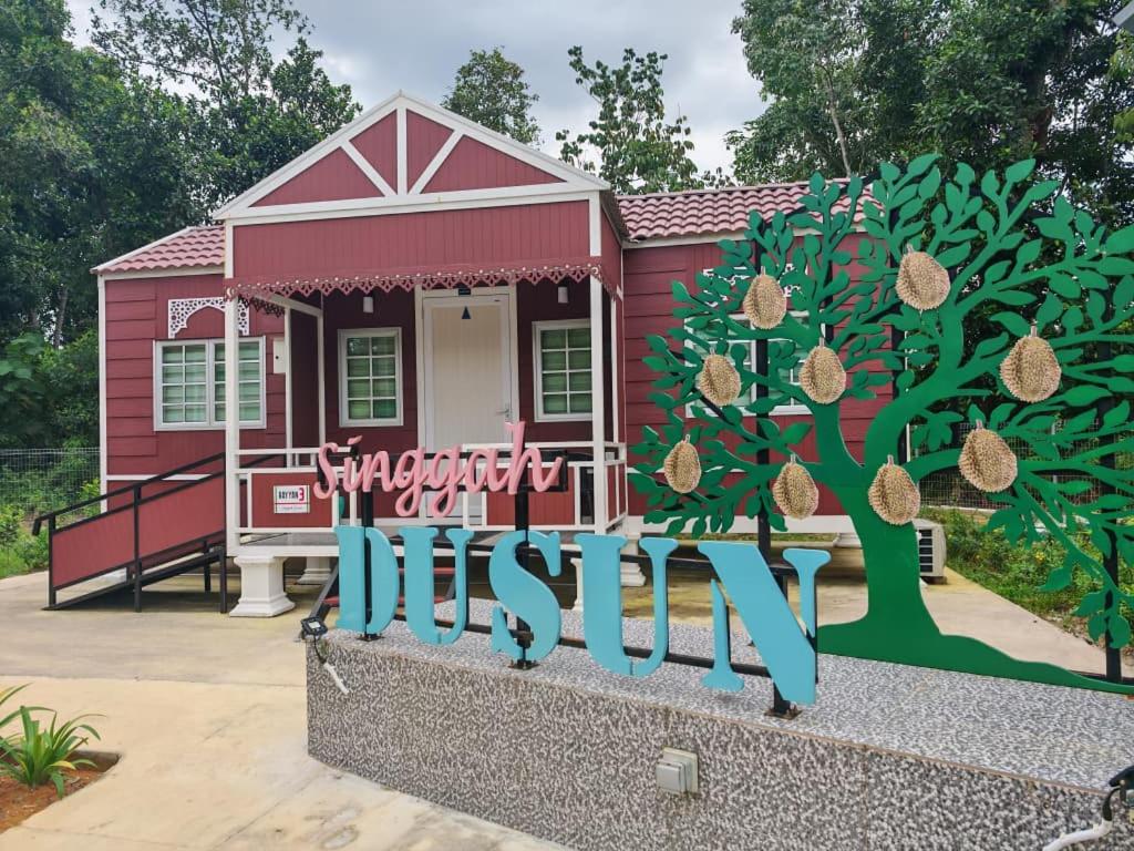 a small red house with a sign in front of it at Singgah Dusun Zahra in Kampong Perak