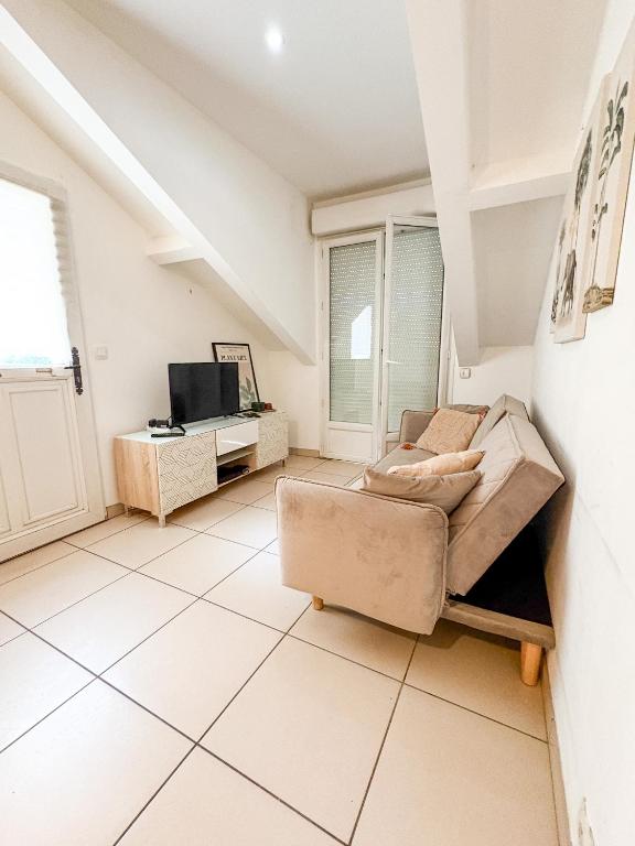 a living room with a couch and a tv at À Quelques pas de la gare - Duplex in Sartrouville