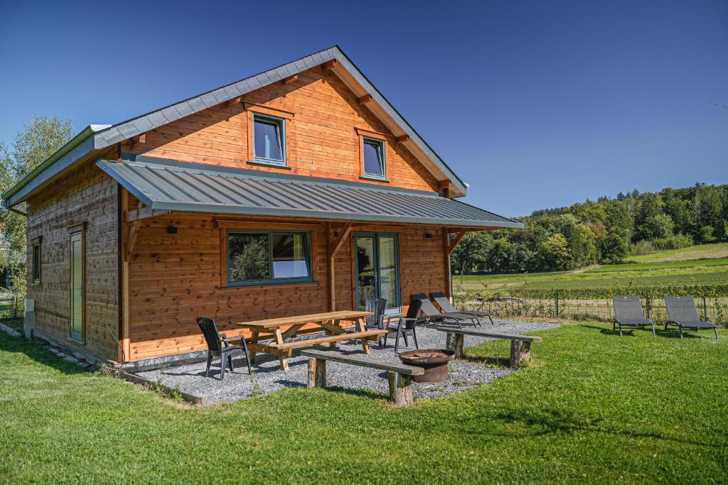 a log cabin with picnic tables and chairs in the grass at Gites de la Semois in Laviot