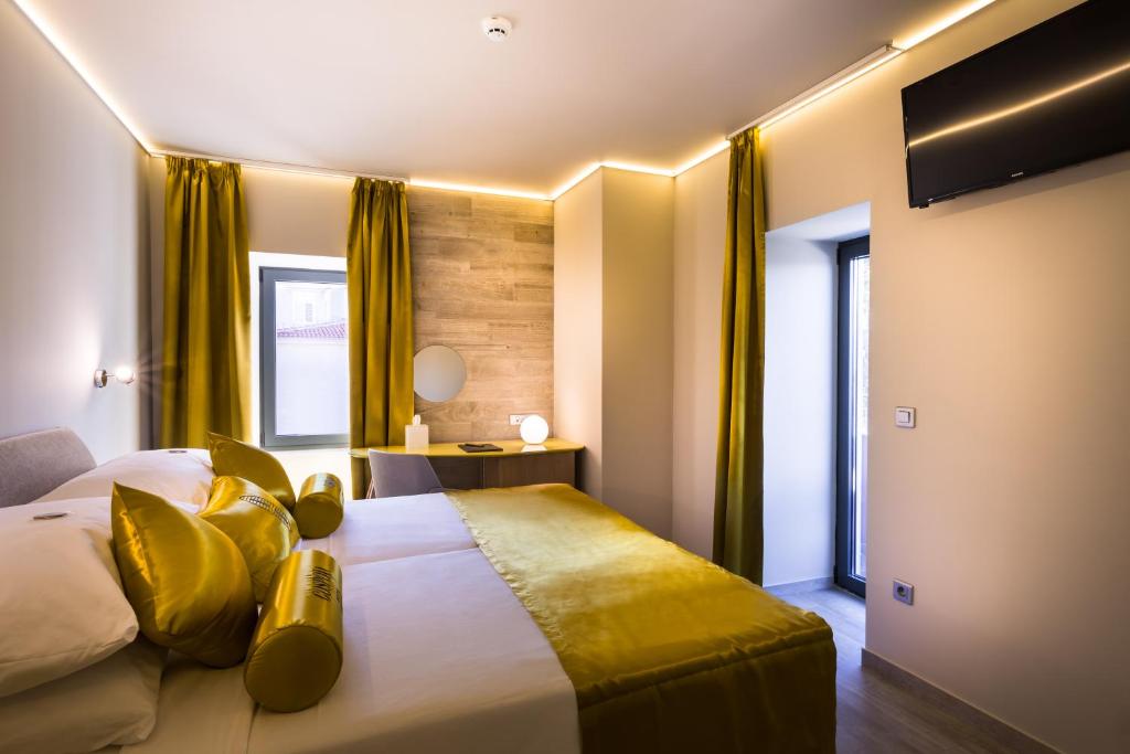 a bedroom with a large bed with yellow pillows at Hotel Vinotel Gospoja in Vrbnik