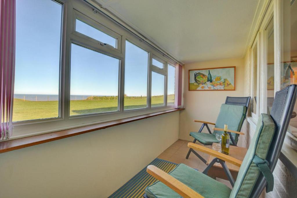 a room with two chairs and a table and windows at 2 Bed in Mundesley oc-673 in Mundesley