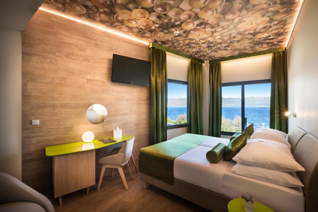 a hotel room with a bed and a desk and windows at Hotel Vinotel Gospoja in Vrbnik
