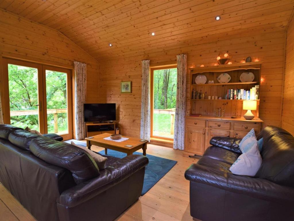 a living room with leather furniture in a log cabin at 3 Bed in Glenfinnan oc-cabin in Glenfinnan