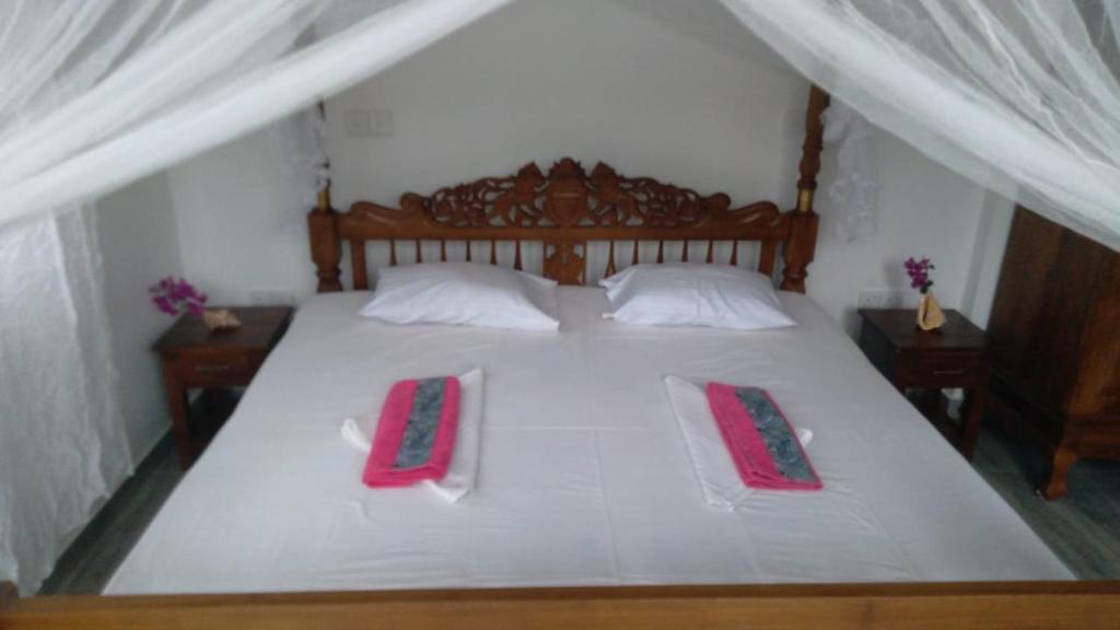 a bedroom with a large white bed with two pillows at Lucky Palace in Beruwala