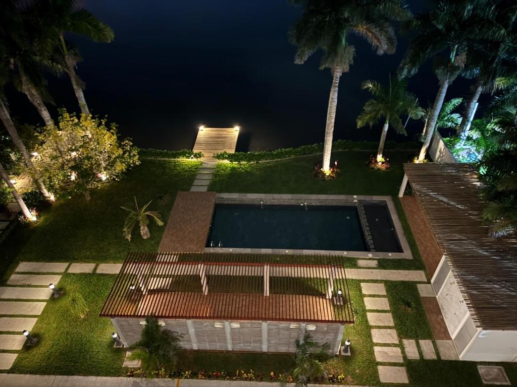 a backyard at night with a swimming pool and palm trees at Depto. 2 rec. con acceso al Río in Boca del Río