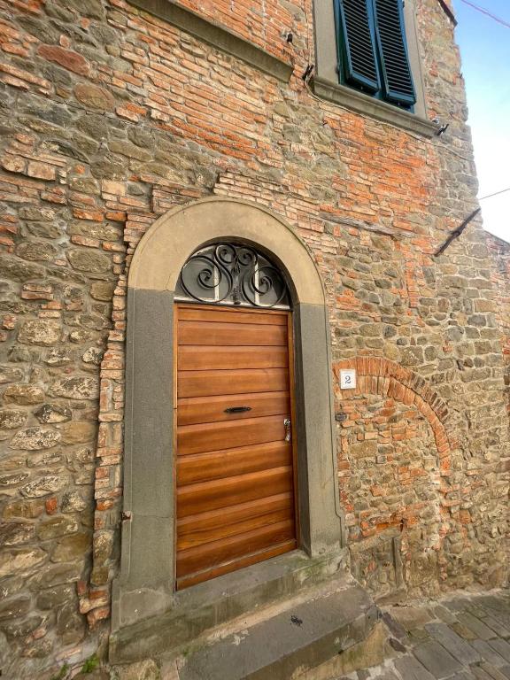 a brick building with a wooden door with an arch at La casa del colle in Colle di Buggiano