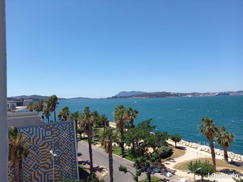 a view of a beach with palm trees and a building at La Goelette 4 in Toulon