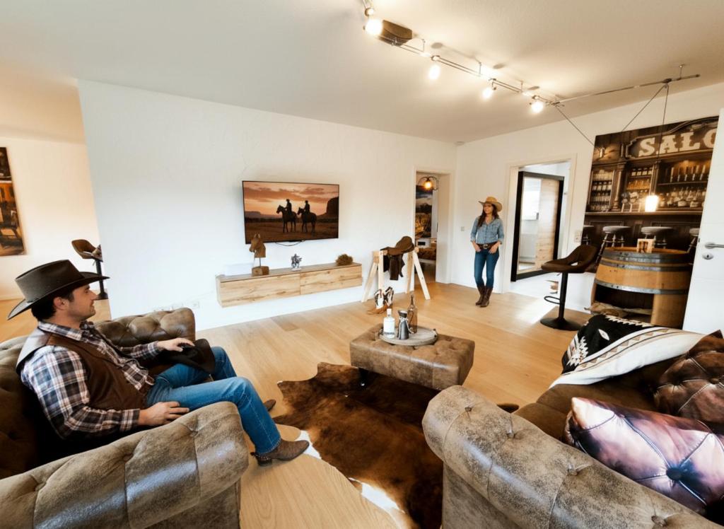 Ein Mann sitzt auf einem Sofa im Wohnzimmer. in der Unterkunft NEU - Wild Western Wohnung - 110 qm umgeben von Pferden am Fluss in Katzweiler