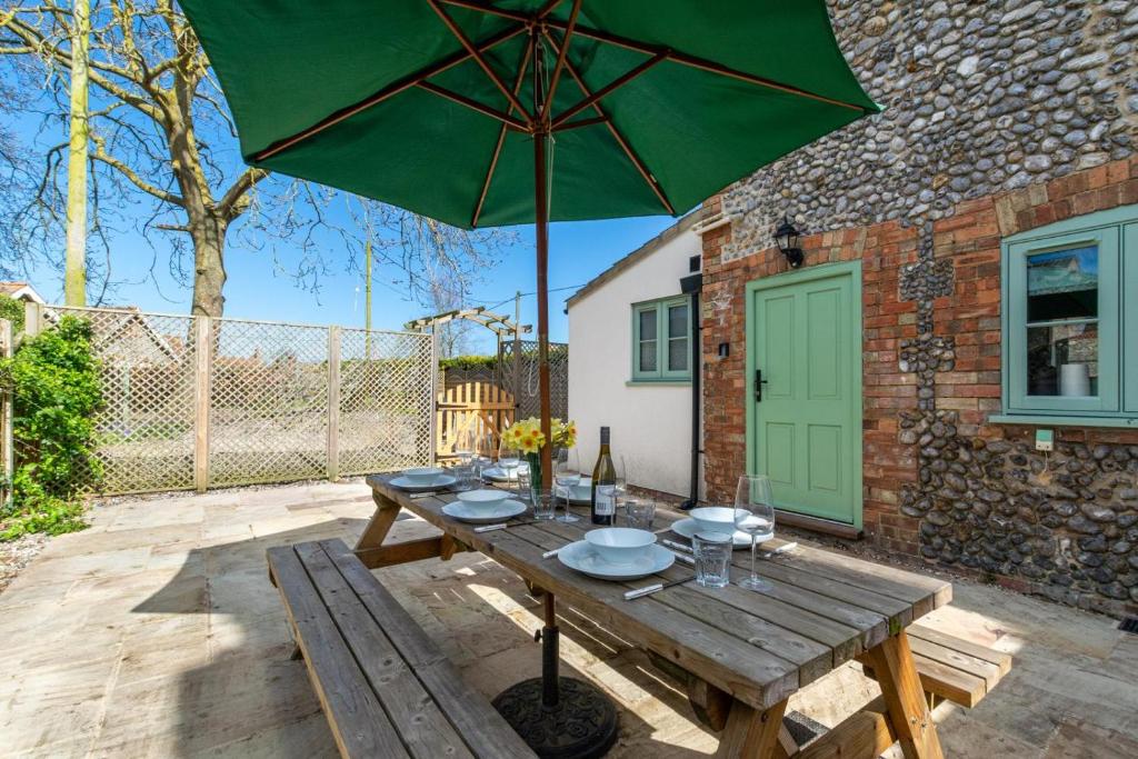 a wooden table with a green umbrella on a patio at 3 Bed in Kelling oc-w27424 in Kelling