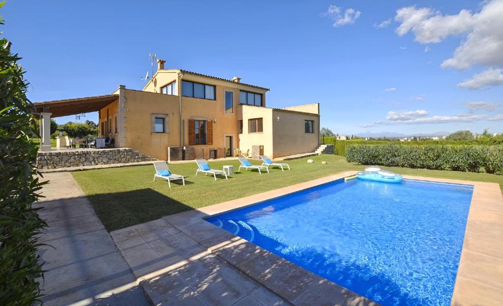 a villa with a swimming pool in front of a house at Llum in Manacor
