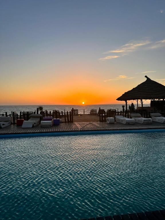 a swimming pool with a sunset in the background at maison d'hôtes la merveille in Dakhla