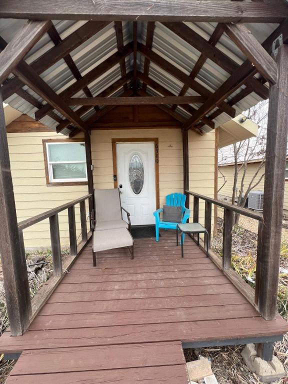a wooden porch with two chairs and a bench on it at Cottage No 4 on Ranch in McKinney