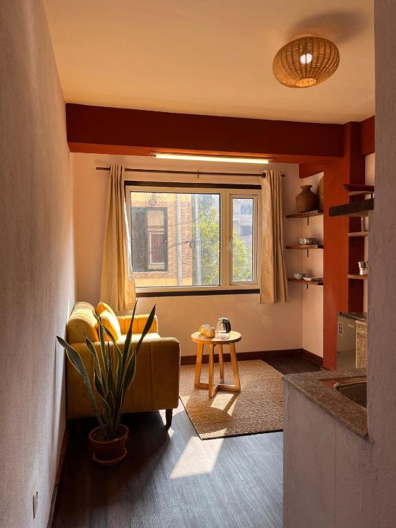 a living room with a yellow couch and a window at Mandāravā Āvāsa in Kathmandu