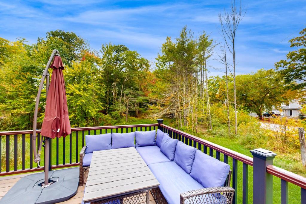 a patio with a couch and an umbrella on a deck at 4-Season Family Base! 13 Mi to Lake Winnipesaukee in Center Barnstead