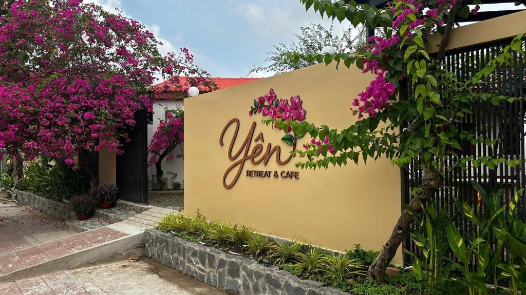 a sign for a restaurant with purple flowers on a fence at Yên Retreat & Cafe in Cà Mau