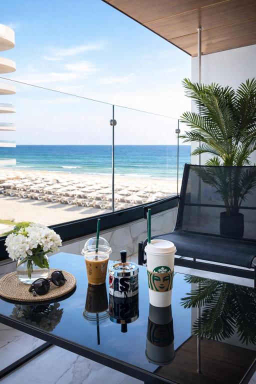 a table with two drinks and a view of the beach at Eva Del Mar - Sea view - Parcare Privata Inclusa in Mamaia