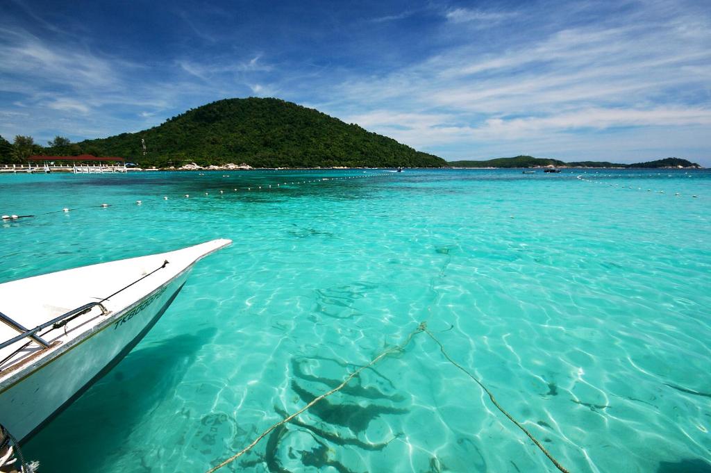 a boat in the water near a small island at Perhentian Island Resort in Perhentian Islands