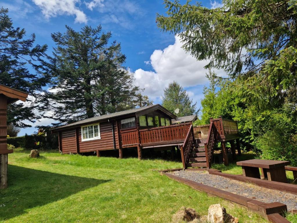 a log cabin in the woods with a yard at Cabin Retreat in Trawsfynydd