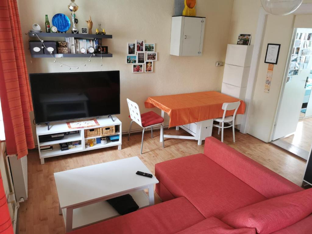 a living room with a red couch and a table at Grenzstübchen in Hötensleben