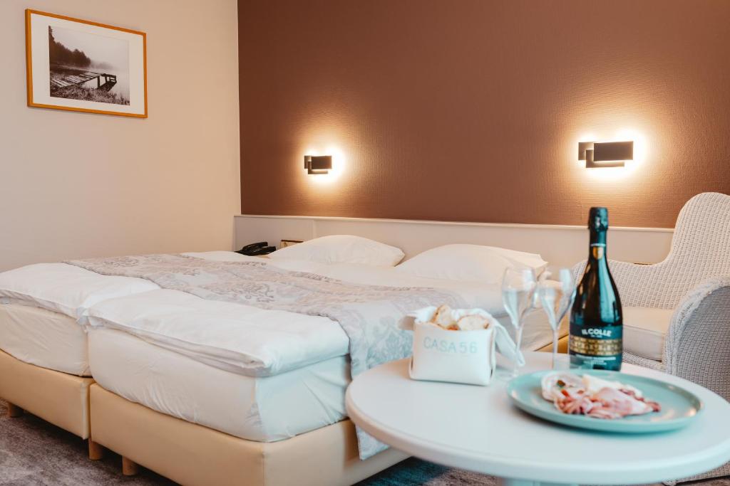 ein Hotelzimmer mit einem Bett und einem Tisch mit einer Flasche Wein in der Unterkunft Hotel Casa56 in Weiswampach