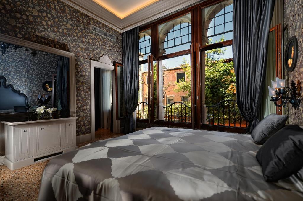 a bedroom with a large bed and a large window at Hotel Palazzetto Madonna in Venice