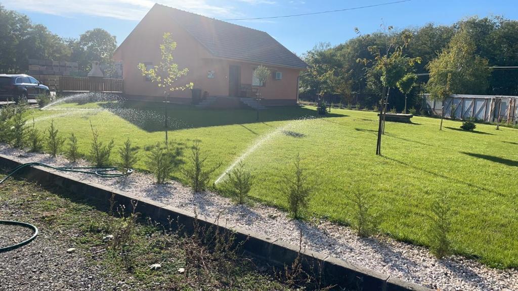 a house with a sprinkler in a yard at Barackvirág-Vendégház in Érpatak