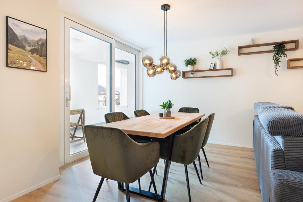 a dining room with a wooden table and chairs at Spacious & Modern Apt - Balcony & Parking in Spiez