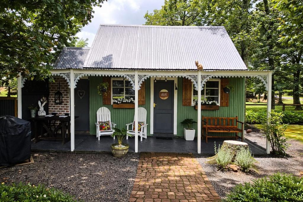 a green house with a porch and a table and chairs at Little Tin House in Van Reenen