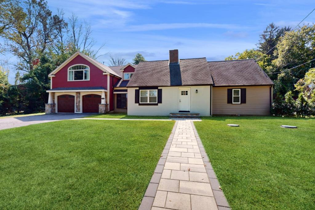 a house with a green yard with a driveway at Game Day Hub < 1 Mi to Stadium & Patriot Place! in Foxborough