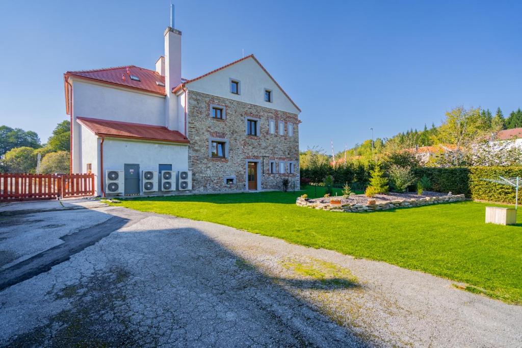 a large stone building with a grass yard and a driveway at Apartmány Polná na Šumavě in Svíba